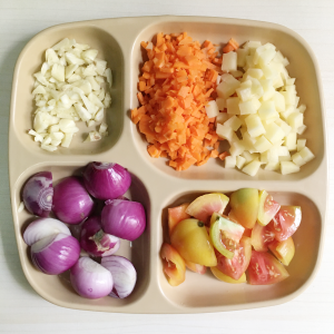 Plate of chopped and sliced ingredients: garlic, tomato, onions, carrots, potatoes