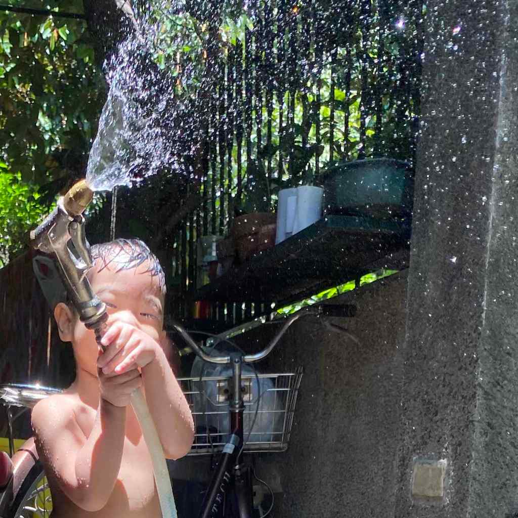 Toddler having fun with a water hose