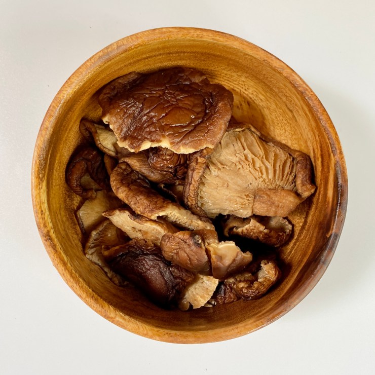 Rehydrated shiitake mushrooms in a wooden bowl.