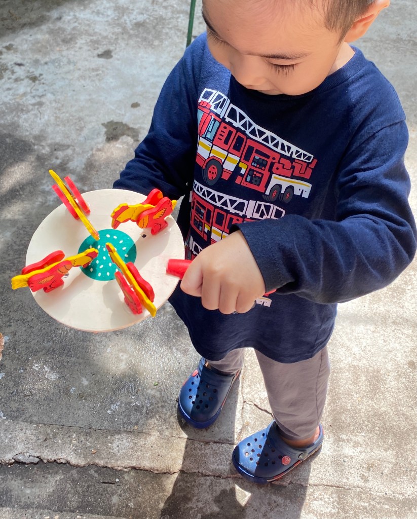 Toddler playing with wooden chicken toy.