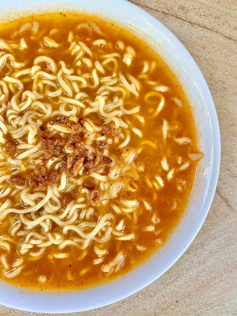 Cooked Mi Sedaap Kari Noodles topped with fried onions