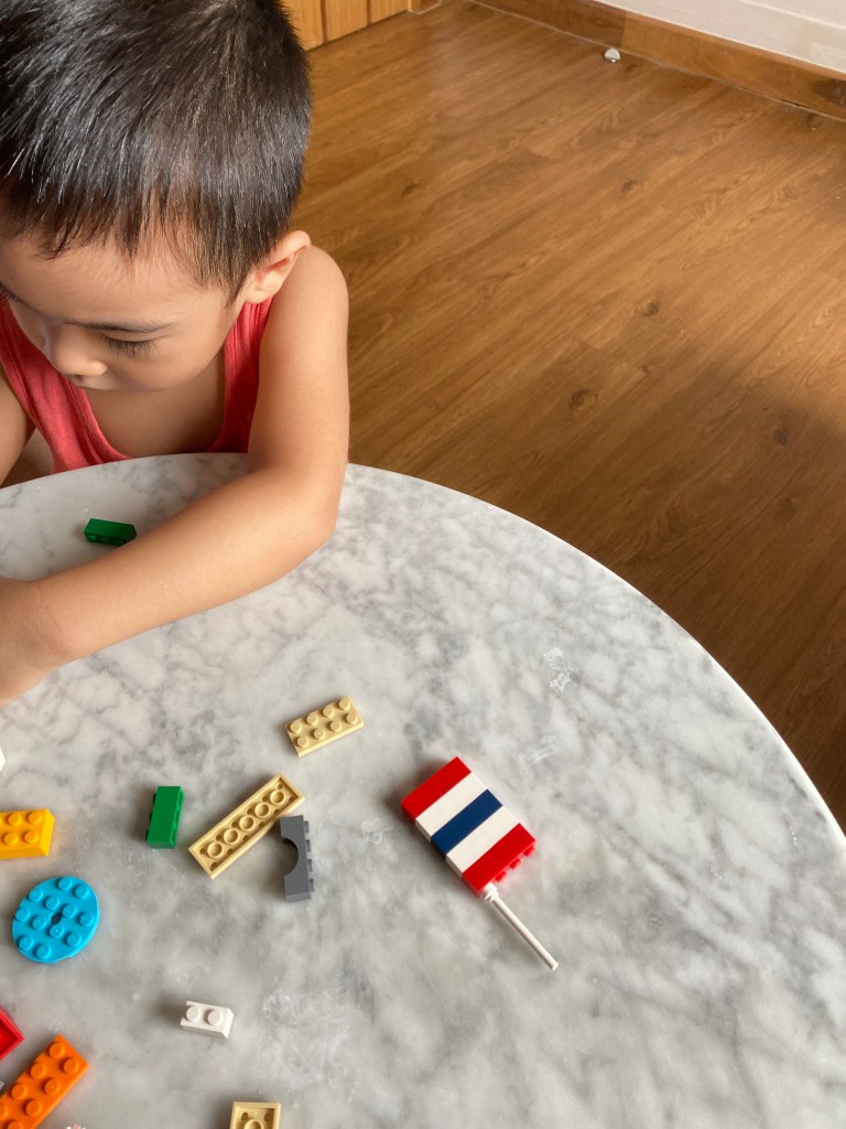 A toddler building the Thai flag using legos.