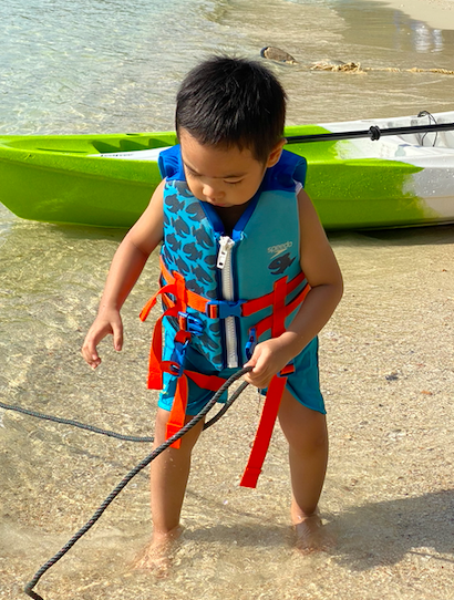 A little boy playing by the kayak