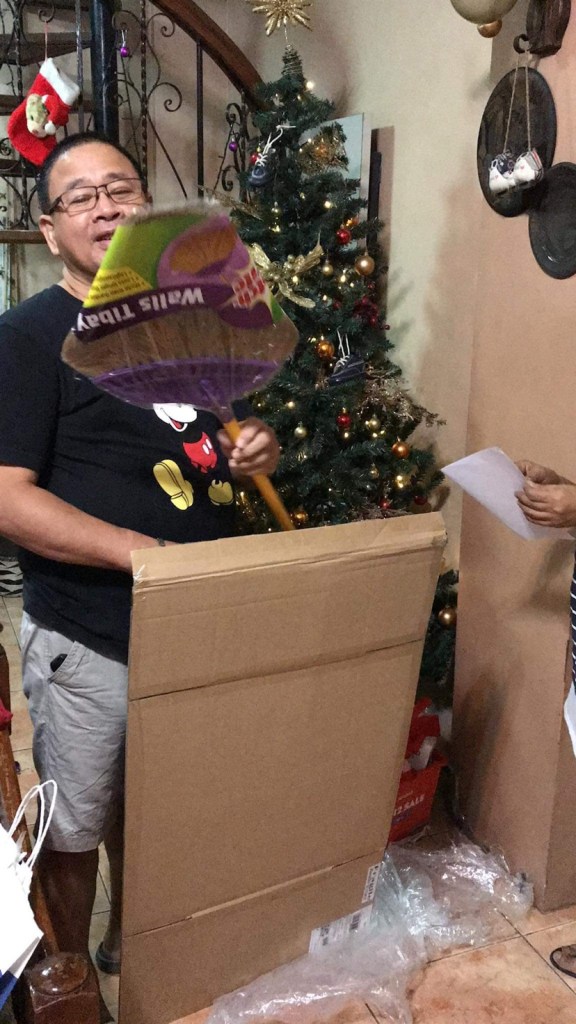 A grand father laughing at his Scotch-Brite Walis Tibay broom as a Christmas gift.