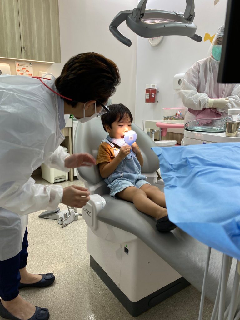 Little boy holding a mirror to check his teeth