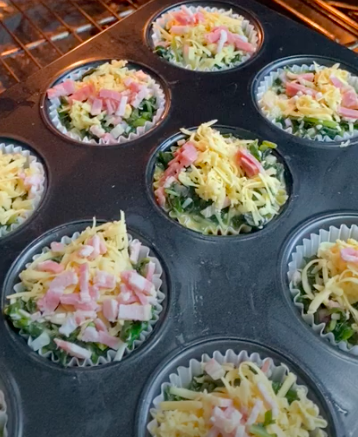 Placing a tray of cheesy spinach egg muffin cups inside an oven.