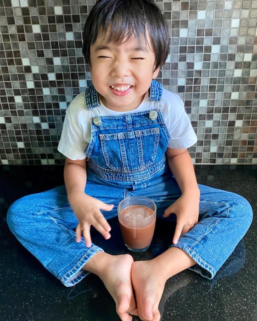 Happy boy in overalls drinking chocolate milk