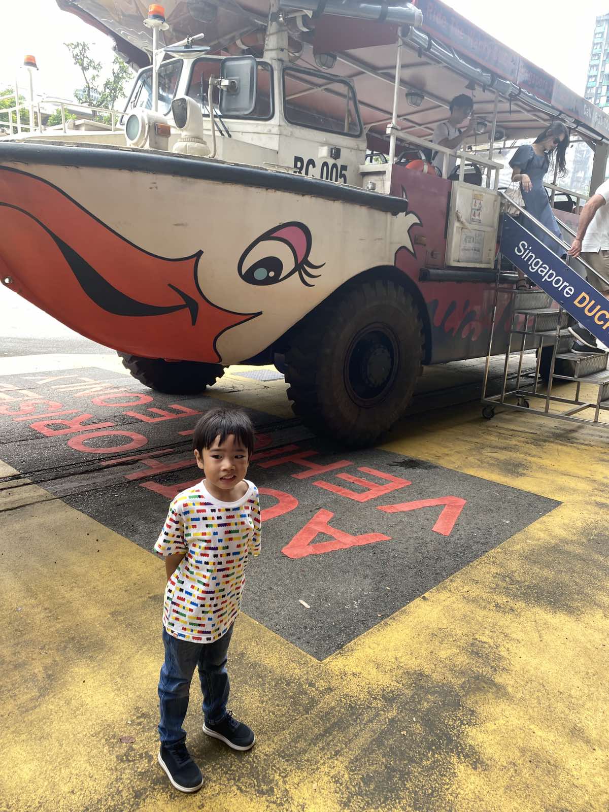 Little boy smiling with an amphibian vehicle behind him