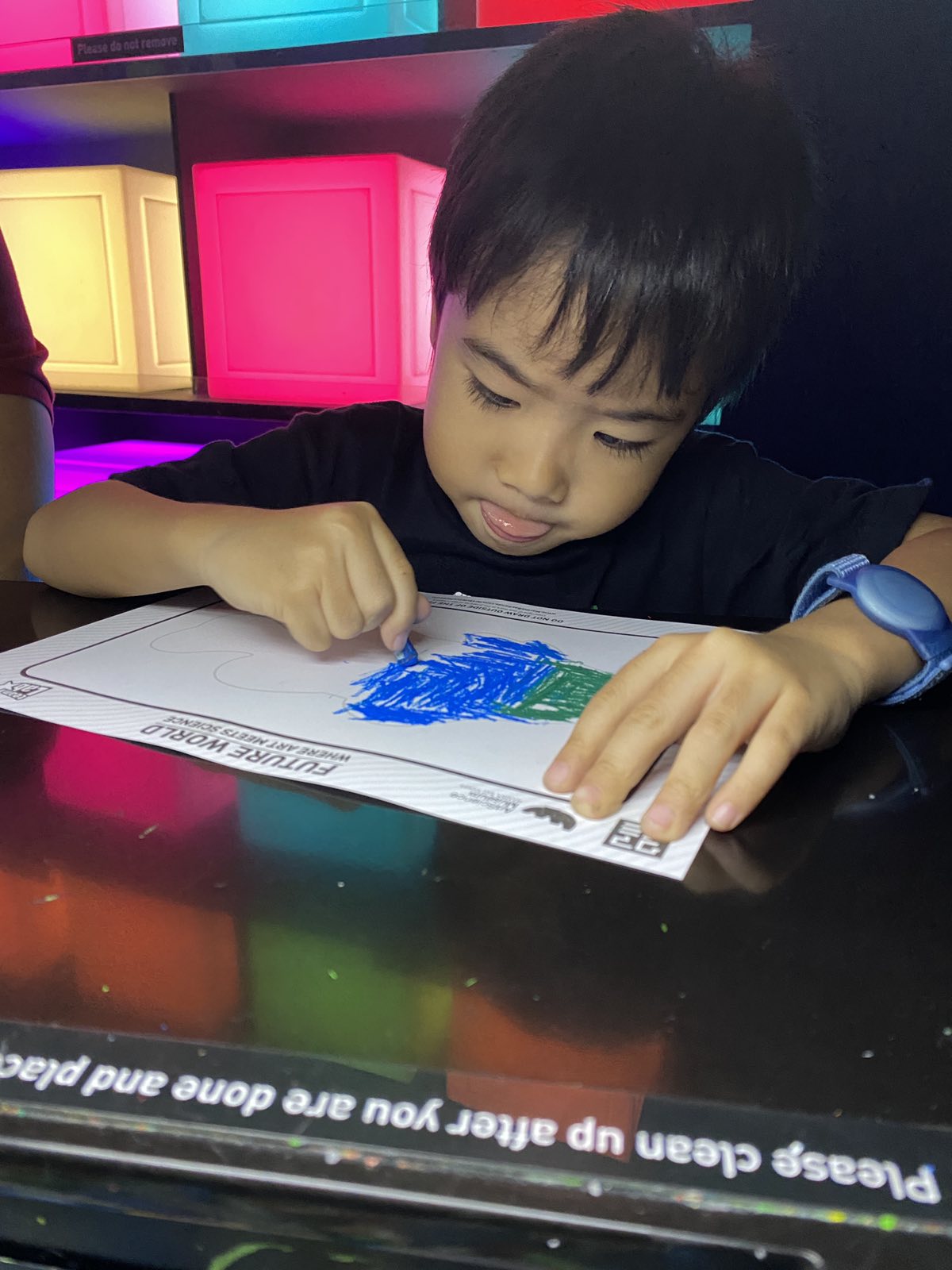 Little boy concentration on his drawing and sticks is tongue out.