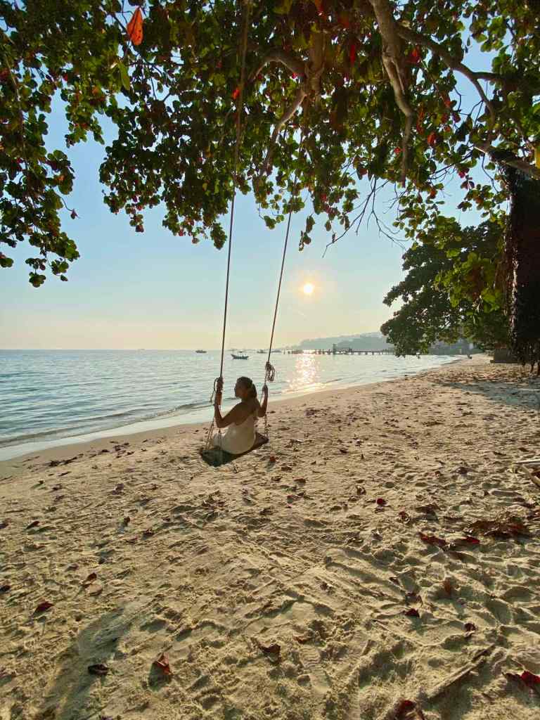Woman riding a rope swing at a beach