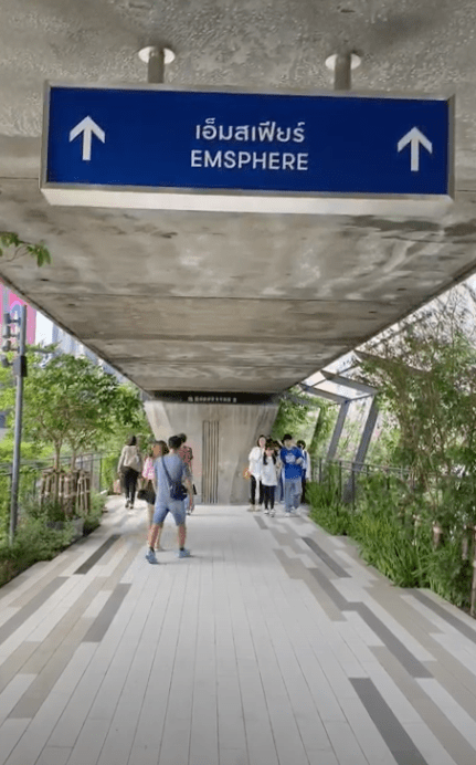 a walkway connecting a train station to a mall with signage