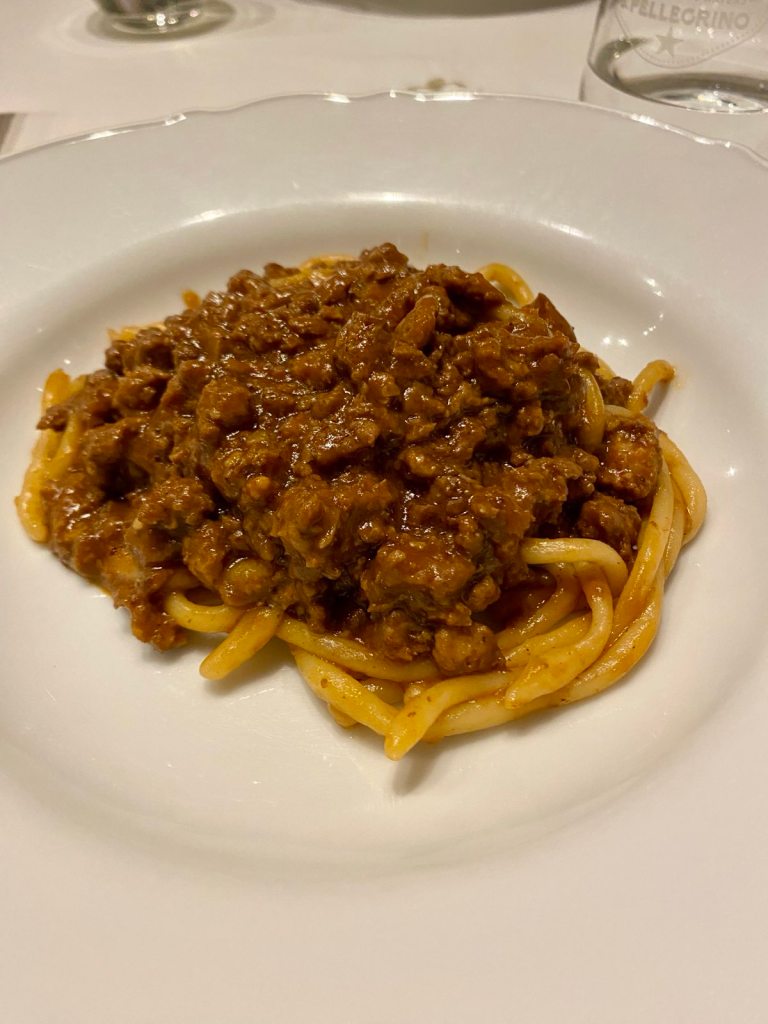 A bowl of authentic handmade pasta topped with thick sauce.