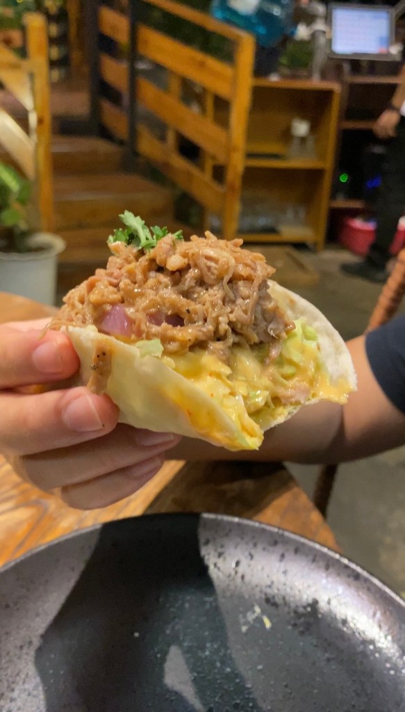 Holding up a bitten pulled pork taco