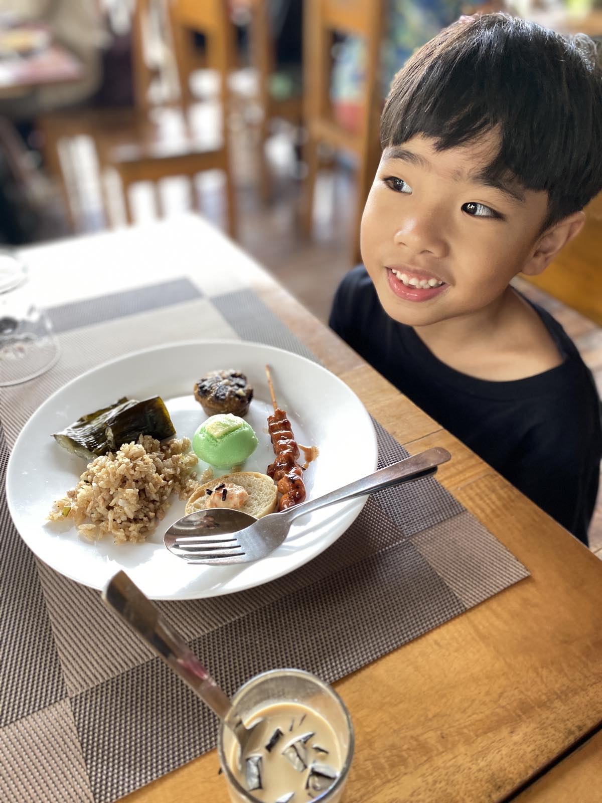 A boy smiling with his plate of Filipino food from a buffet