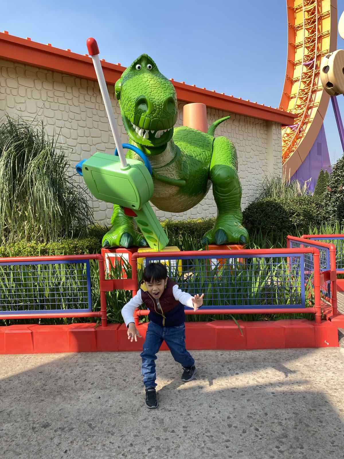 boy roaring under a dinosaur statue