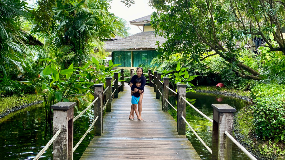 Mom and son hugging on a wooden bridge in a tropical resort