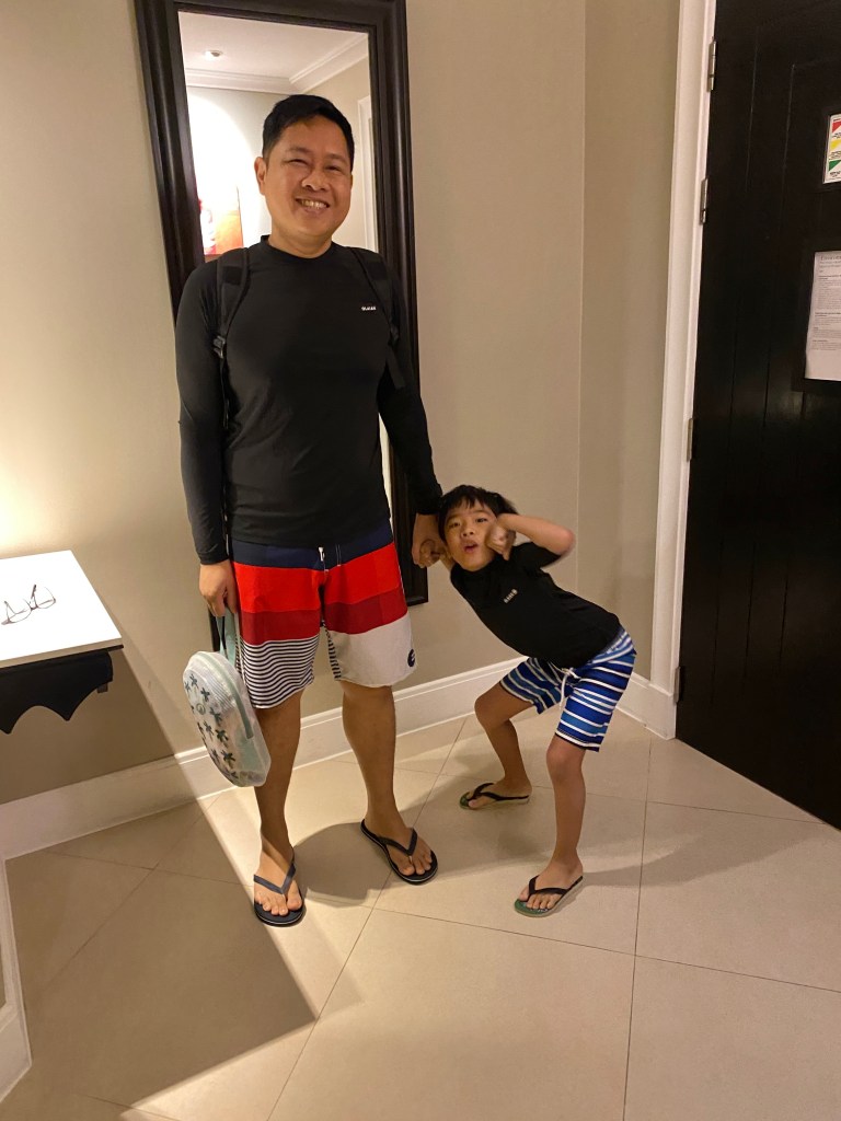 A father and son wearing swim clothes getting ready to go out