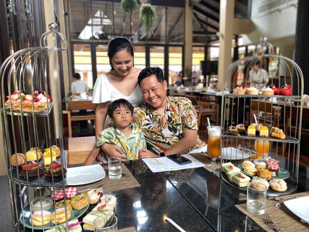 A family having a high tea at a restaurant surrounded with pastries.