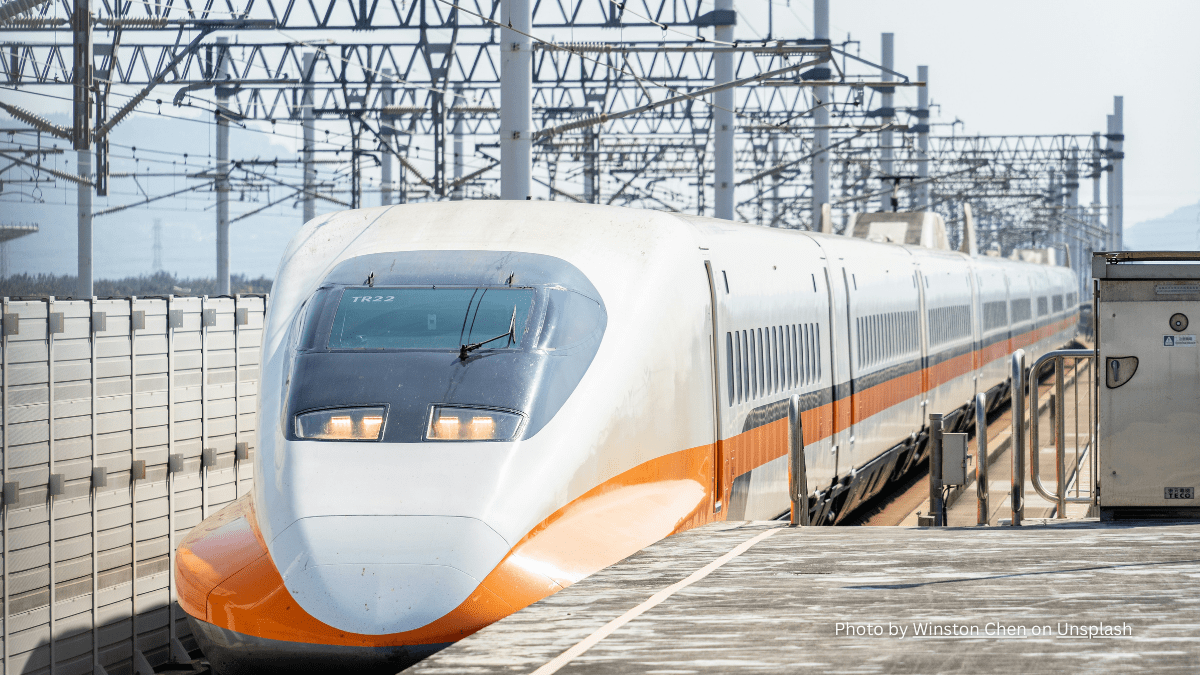 A white and orange Taiwan High Speed Rail Train approaching a terminal